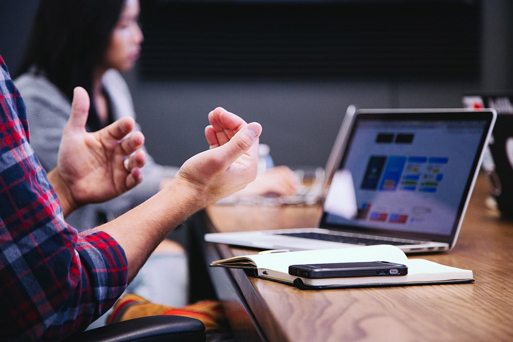 man making a hand gesture while working on laptop