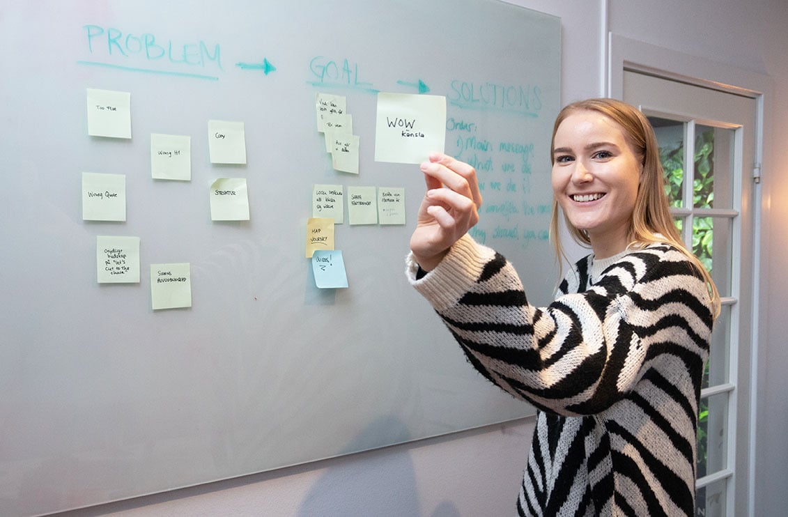 UX designer holding post-it note solving a problem on whiteboard